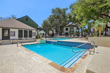A swimming pool surrounded by a concrete floor and a metal railing.
